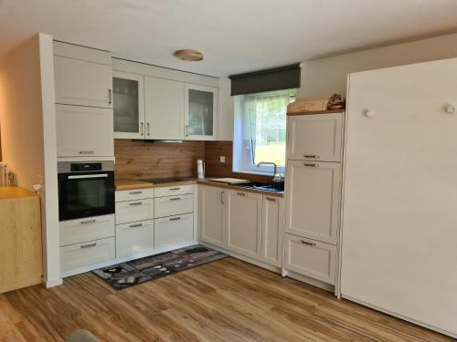 a kitchen with white cabinets and a refrigerator at Apartments Haus Quelle in Leukerbad