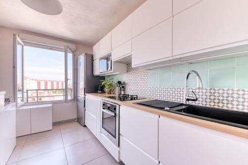 uma cozinha com armários brancos e uma grande janela em Le spacieux proche part Dieu em Villeurbanne