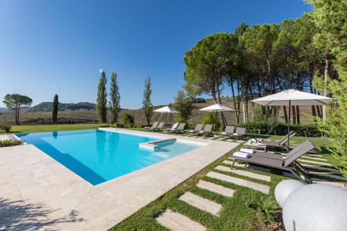 a swimming pool in a yard with chairs and an umbrella at PODERE BELLARIA 18&2, Emma Villas in Rapolano Terme