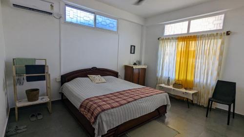 una camera con un letto e due finestre e una sedia di Golpo - Stories and Stays a Dibrugarh