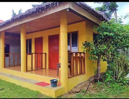 a small yellow house with a wooden deck at Gold Star Inn in Siquijor