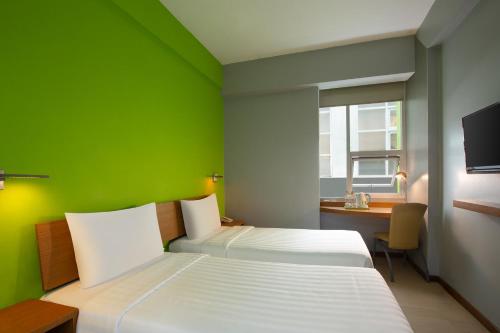 a bedroom with two beds and a desk and a green wall at Whiz Hotel Malioboro Yogyakarta in Yogyakarta