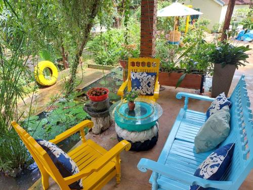 un patio con mesa y sillas azules y amarillas en The Lazy Farm - Homestay & Glamping, en Mewal