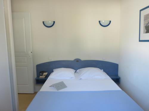 a bed with a blue headboard with a paper on it at Résidence Goélia Les Demeures du Lac in Casteljaloux