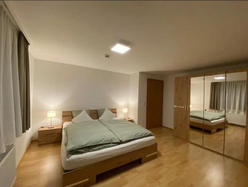 a bedroom with a bed with two lamps and a mirror at Bodensee Wohnung 2 mit Privatstrand in Gaißau