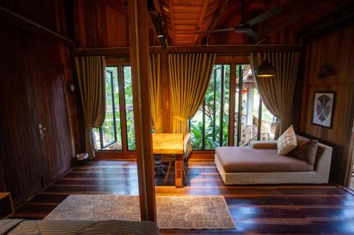 a living room with a couch and a bed and windows at Khmer Oasis on the Lake 