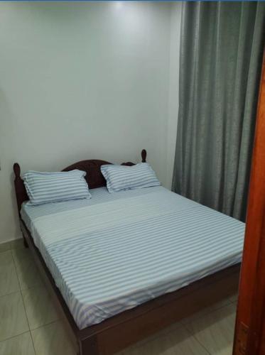1 cama con 2 almohadas junto a una ventana en IP House en Kigali