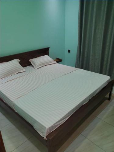 1 dormitorio con 1 cama grande con sábanas blancas en IP House en Kigali