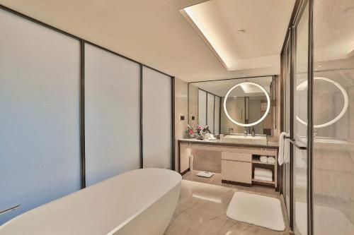 a bathroom with a tub and a sink and a mirror at Narada Grand Hotel Zhejiang in Hangzhou