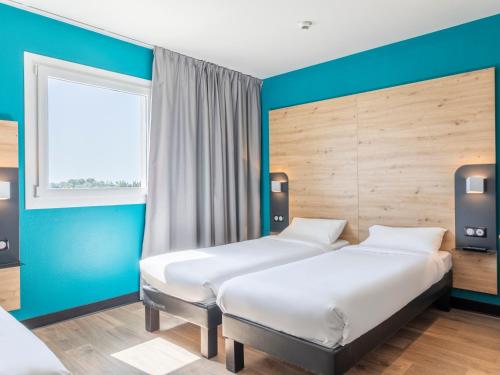 2 letti in una camera con pareti blu di B&B HOTEL Saint-Martin-de-Crau Alpilles Camargue a Saint-Martin-de-Crau