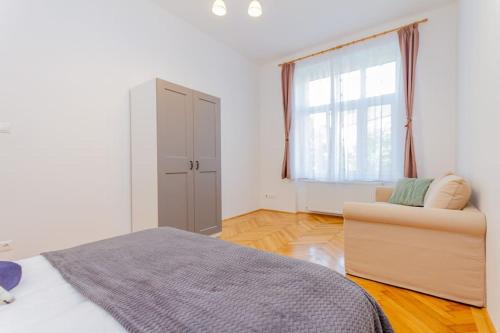 a bedroom with a bed and a chair and a window at Bartók Boulevard Apartment by NW in Budapest