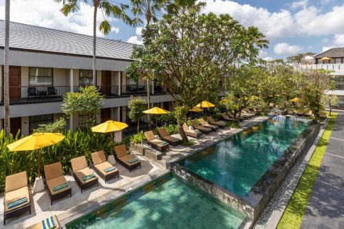 an image of a hotel pool with chairs and umbrellas at Amadea Resort & Villas Seminyak Bali in Seminyak