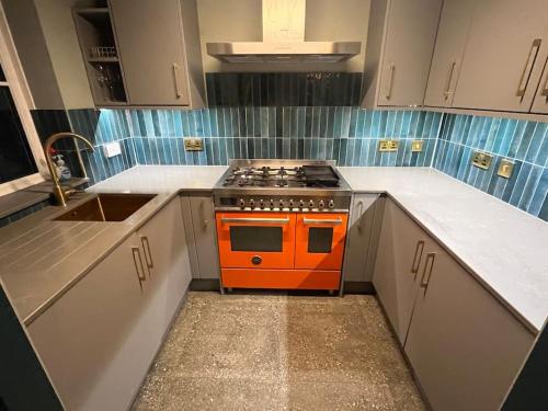 an orange stove in a kitchen with white cabinets at The Coachhouse, Hot Tub in Henley in Arden