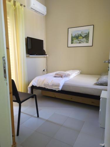 um pequeno quarto com uma cama e uma cadeira em Ο κόκορας em Artemida