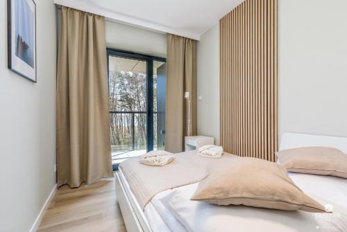 a bedroom with two beds and a large window at Shellter Apartments 117 H - by Jantar Apartamenty in Rogowo