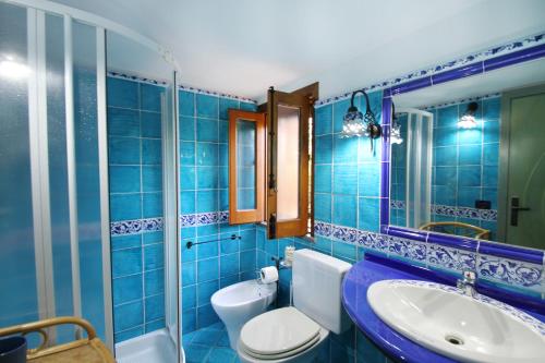 a blue tiled bathroom with a toilet and a sink at BOUTIQUE VILLA con accesso privato alla spiaggia in Caronia