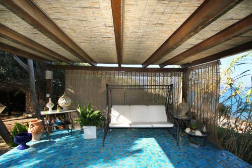 a patio with a white bed and some plants at BOUTIQUE VILLA con accesso privato alla spiaggia in Caronia