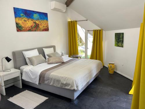 a bedroom with a large bed with yellow curtains at Résidence la Pyramide in Oberhaslach