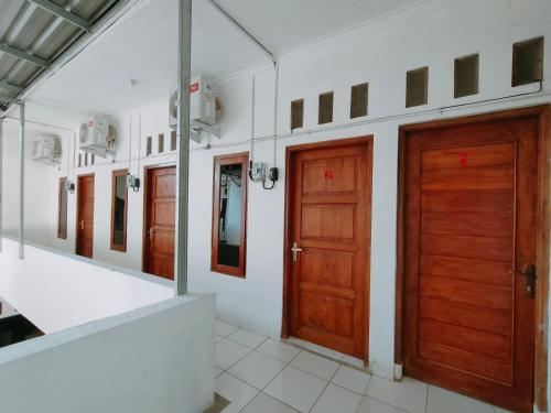 two wooden doors in a room with white walls at RedDoorz Syariah near Jogja Expo Center in Demangan