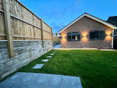 een stenen huis met een hek en een tuin bij Modern bungalow in good location in Aberdulais
