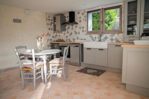 een keuken met een tafel en stoelen en een wastafel bij Charmant Appartement T2 Parking & Terrasse - Crêt de la Roche in Aix-les-Bains