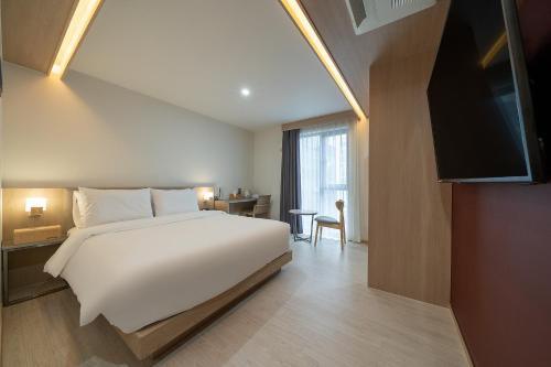een slaapkamer met een groot wit bed en een televisie bij Hound Hotel Gimhae Samgye in Gimhae