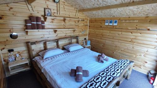 1 dormitorio con 1 cama en una cabaña de madera en Edelweiss guesthouse, glamping and camping en Suhaia