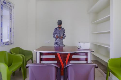 a person standing in front of a table with chairs at Flagship Sri Residency in Dhundgol