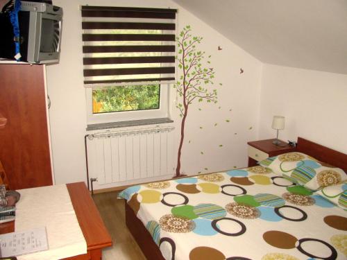 a bedroom with a bed and a window with a tree on the wall at House Sekulic in Grabovac