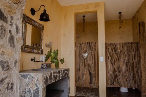 a bathroom with a stone fireplace and a mirror at Casa Jasmin Bed & Breakfast in Troncones