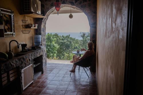 una donna seduta a un tavolo in una cucina con vista di Casa Jasmin Bed & Breakfast a Troncones