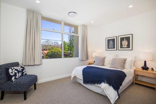 a bedroom with a bed and a window and a chair at Camellia - Pet Friendly - 3 Min Walk to Centre of Berry in Berry
