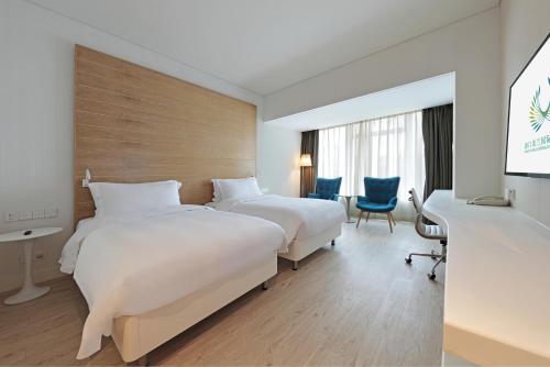 a hotel room with two beds and a desk at Haikou Meilan International Airport Hotel in Haikou