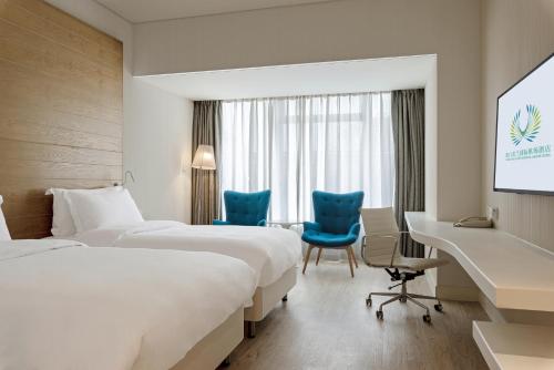 a hotel room with two beds and a desk and chairs at Haikou Meilan International Airport Hotel in Haikou