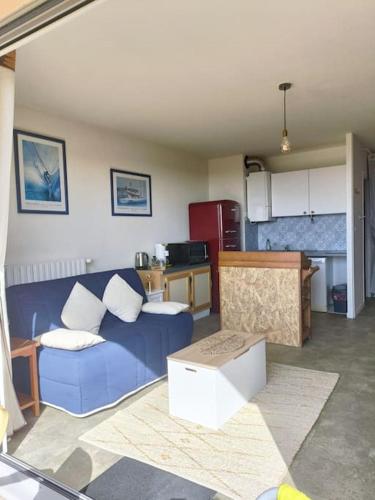 un salon avec un canapé bleu et une cuisine dans l'établissement Le Studi O, à La Chaume