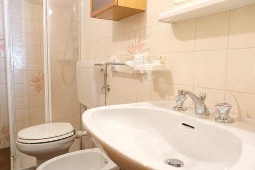 ein weißes Bad mit einem WC und einem Waschbecken in der Unterkunft Gran Vernel Hause in Canazei