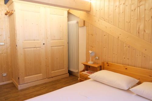 ein Schlafzimmer mit einem Bett und einer Holzwand in der Unterkunft Gran Vernel Hause in Canazei