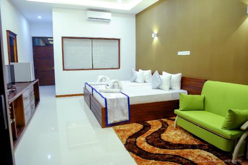 a bedroom with a bed and a couch and a television at Saru Blue Sapphire Hotel in Godakewela