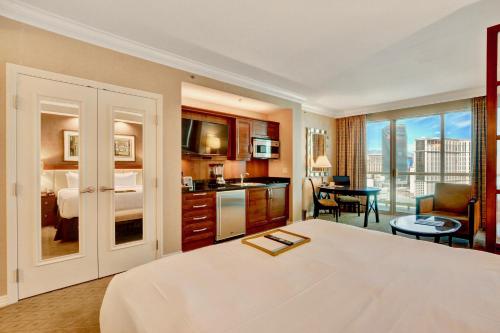 a hotel room with a large bed and a kitchen at Strip View Balcony Suites - No Resort Fee ! in Las Vegas