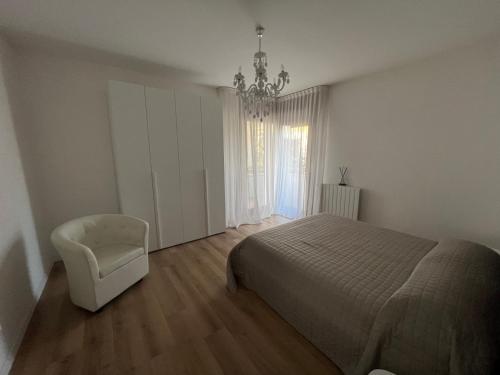 a bedroom with a bed and a chair and a chandelier at Ca’ Uccelli-Stupendo Appartamento 5 min da Venezia in Marghera