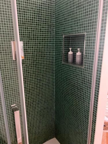 a green tiled bathroom with two bottles on a shelf at Ca’ Uccelli-Stupendo Appartamento 5 min da Venezia in Marghera