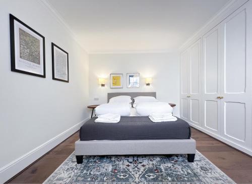 um quarto branco com uma cama com almofadas brancas em Museum ST Central Soho Apartment em Londres