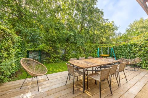 une table et des chaises en bois sur une terrasse en bois dans l'établissement Nice house with a yard and common pool - Deauville - Welkeys, à Deauville