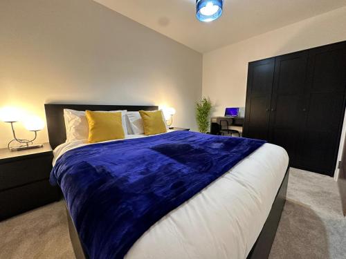 a bedroom with a large bed with a blue blanket at 1 Bed Apartment near Old Trafford with free car park in Manchester