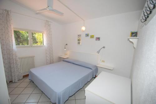 a white bedroom with two beds and a window at Azienda Agricola Sapereta in Porto Azzurro