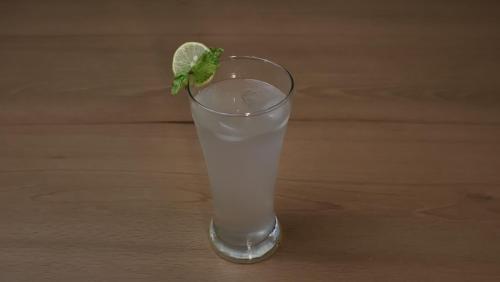 a glass of lemonade with a lime on a wooden table at Hotel Shree Meghdootam in Bhopal