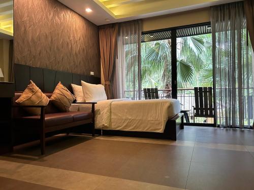 a bedroom with a bed and a couch and windows at Aonang Hill Krabi-SHA Extra Plus in Ao Nang Beach