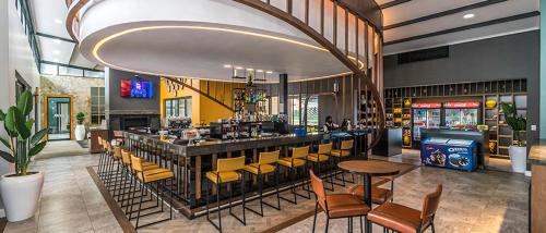 un restaurant avec un bar et des chaises jaunes dans l'établissement Kikuyu Lifestyle Escapade de Luxe, à Midrand