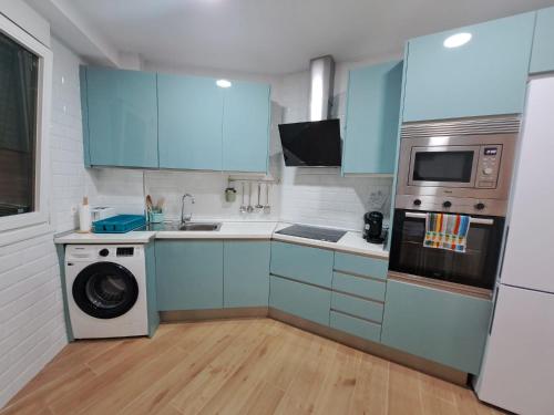 cocina con armarios azules, lavadora y secadora en Apartamento Encanto, en Bermeo