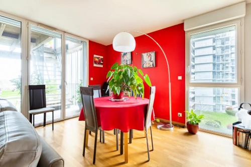 uma sala de jantar vermelha com uma mesa e cadeiras vermelhas em Location chambre privée avec salle de bain et WC privatifs dans appartement moderne em Nantes